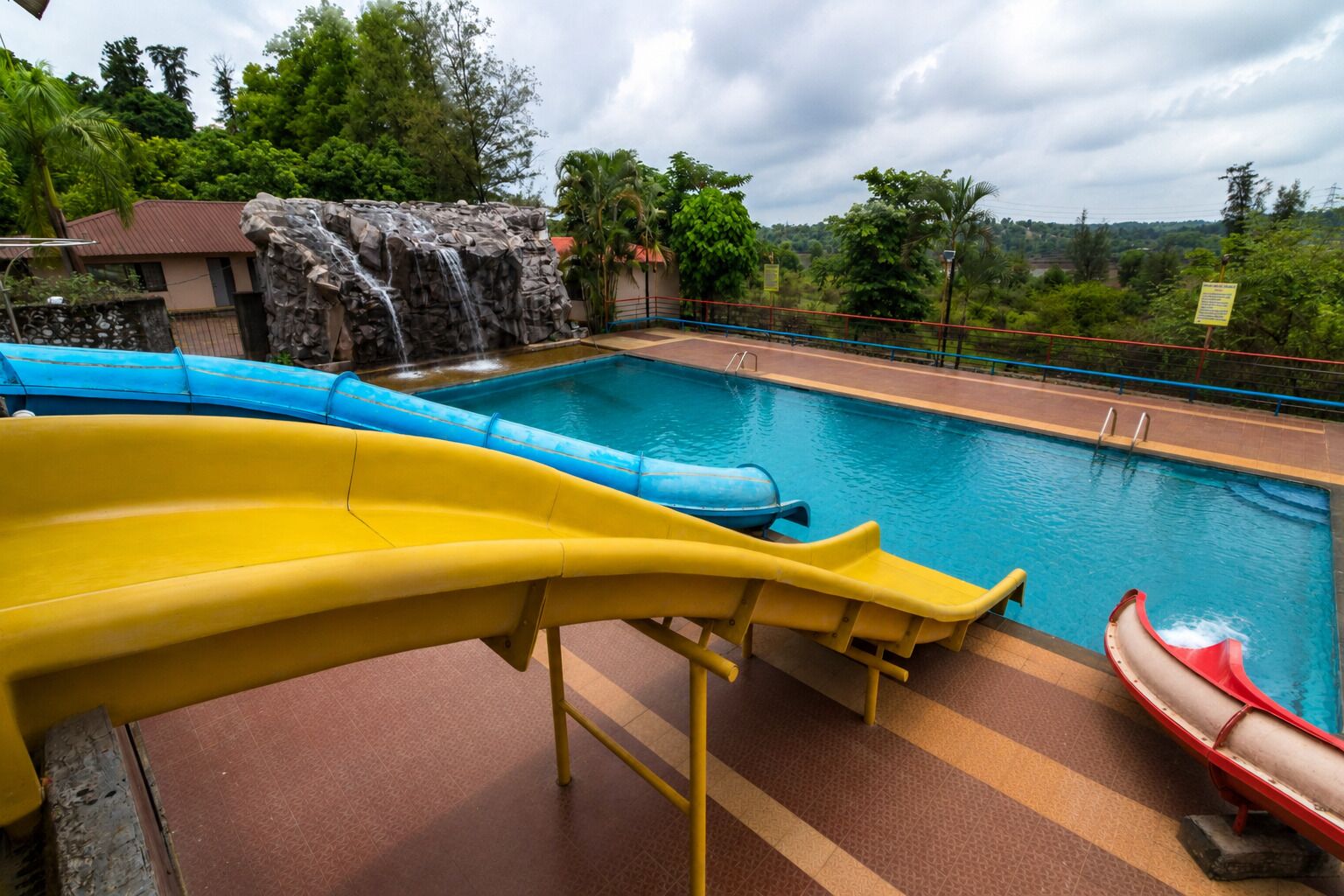 Zona de piscina con toboganes y una cascada.