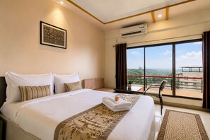 Habitación de hotel con una cama grande, una ventana con vistas, un aire acondicionado y un cuadro en la pared.