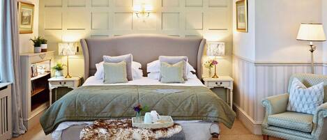 A well-appointed bedroom with a large bed, bedside tables with lamps, a chair, and a decorative fur throw.
