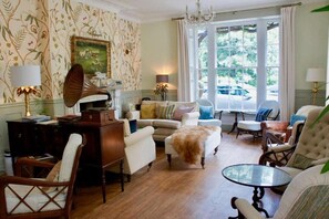 A traditional room with a fireplace, a sofa, a coffee table, and a large window with a view of the outside. - Burleigh Court Cotswolds (Stroud)