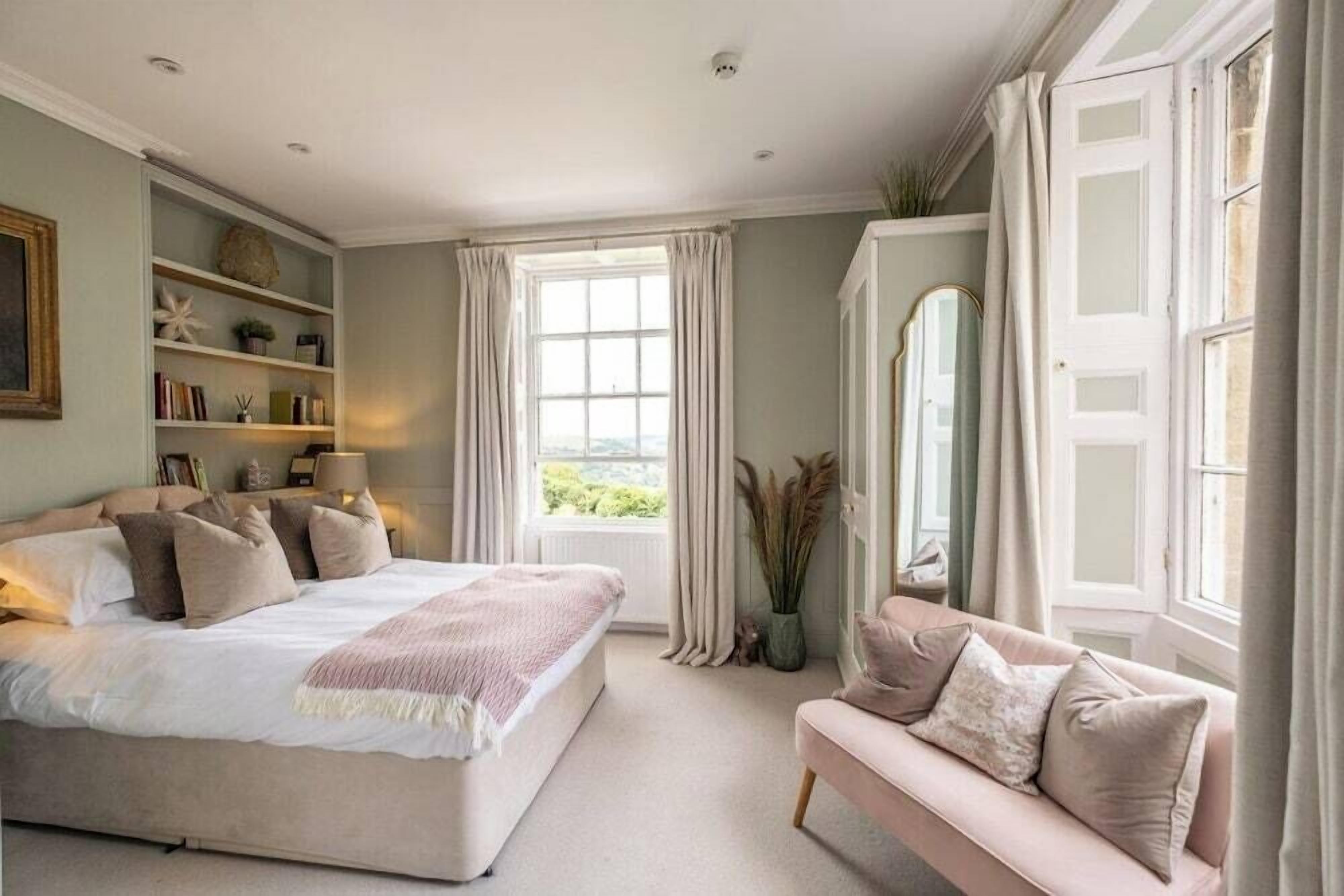Une chambre à coucher avec un lit, un canapé, une fenêtre et une bibliothèque.