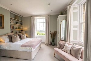 Un dormitorio con cama, sofá, ventana y estantería.