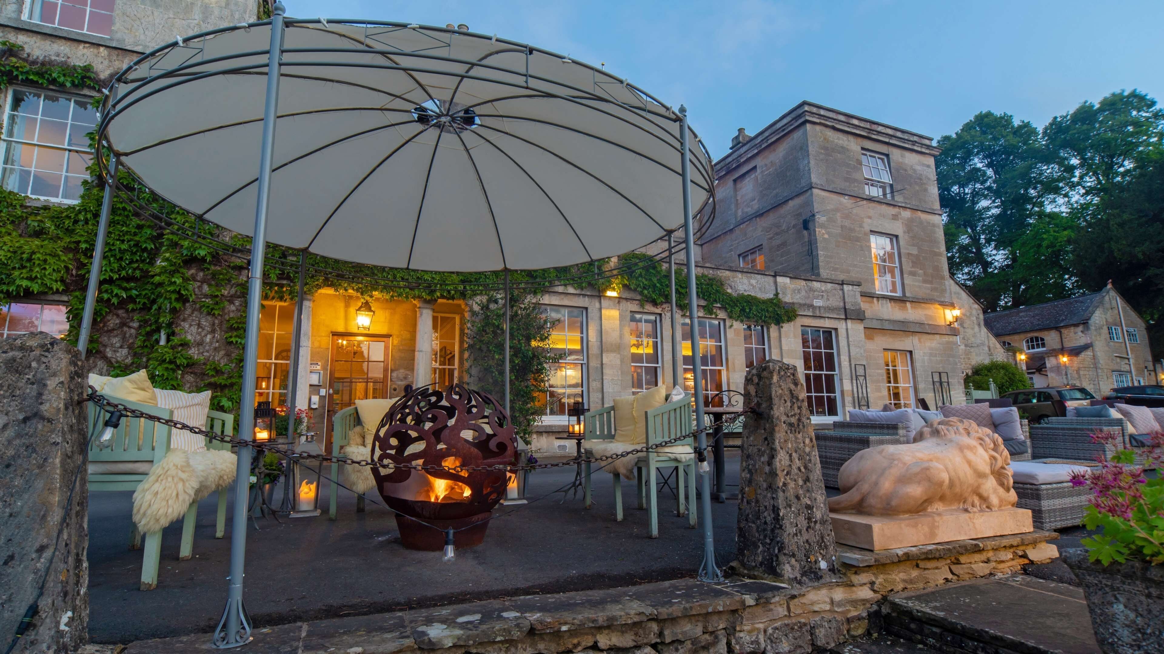 An outdoor seating area with a fire pit, a large umbrella, and stone sculptures.