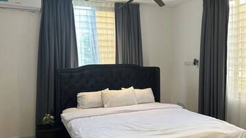 Un dormitorio con cama, ventilador de techo y ventana con cortinas.