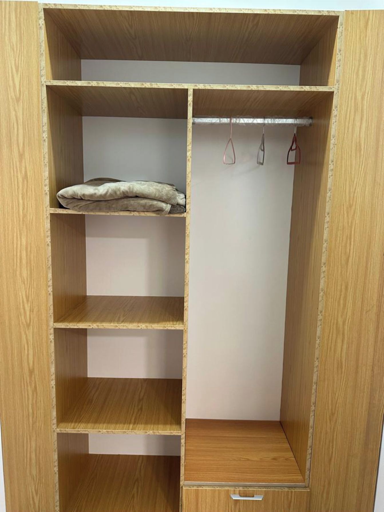A wooden wardrobe with multiple shelves and a hanging rod.
