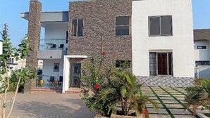 A modern two-story building with a stone facade, a balcony, and a gated entrance. - BGG Havens (Accra)