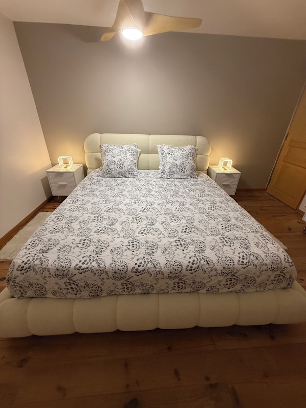 A bedroom with a bed, two bedside tables, and a ceiling fan.