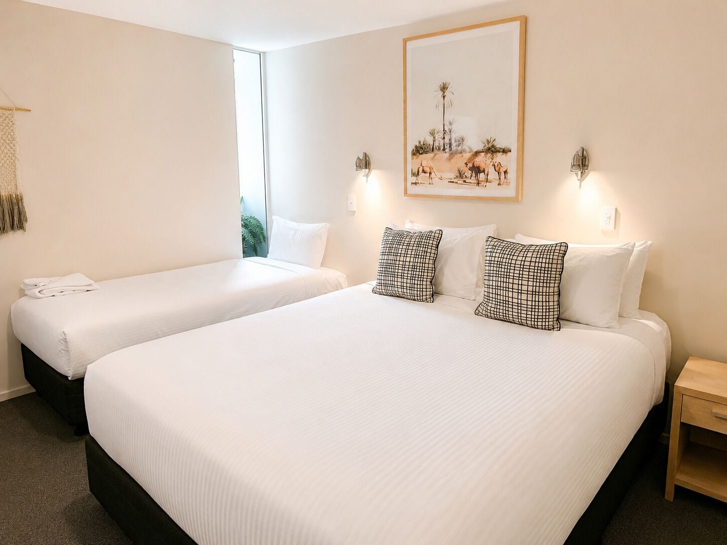 Ein Hotelzimmer mit zwei Betten, einem Nachttisch und einer Wandlampe.