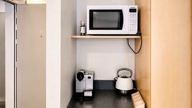 Una cocina con microondas, hervidor y un pequeño electrodoméstico en la encimera.
