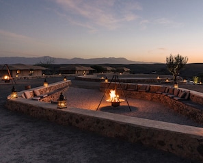 A desert resort with outdoor seating areas, stone walls, and a fire pit. - Caravan by Habitas Agafay (Agafay)