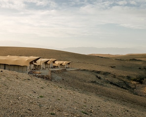 A desert landscape with multiple tents arranged in a row. - Caravan by Habitas Agafay (Agafay)