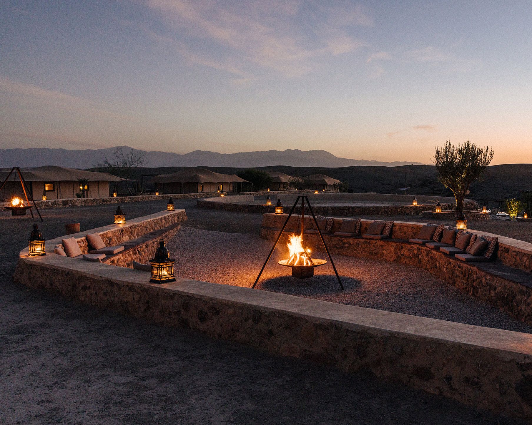 Un resort en el desierto con zonas de estar al aire libre, muros de piedra y una chimenea.