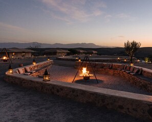 A desert resort with outdoor seating areas, stone walls, and a fire pit. - Caravan by Habitas Agafay (Agafay)