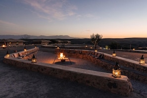 A desert resort with outdoor seating areas, a central fire pit, and lanterns. - Caravan by Habitas Agafay (Agafay)