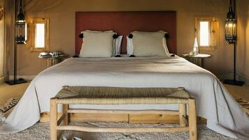 Un dormitorio con una cama grande, dos mesitas de noche, un banco y un par de zapatos.