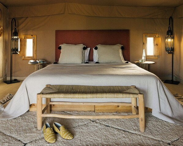 A bedroom with a large bed, two bedside tables, a bench, and a pair of shoes. - Caravan by Habitas Agafay (Agafay)