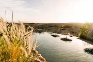 A water feature with a pathway, surrounded by grass and a clear sky. - Caravan by Habitas Agafay (Agafay)
