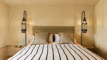 Habitación de hotel con cama, dos mesitas de noche, cabecera de mimbre y dos faroles de pared.