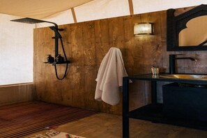 Un baño con pared de madera, ducha, lavabo y una toalla colgada.