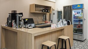 Espaço bar com máquina de café, resfriador de vinhos e dispensador de bebidas.