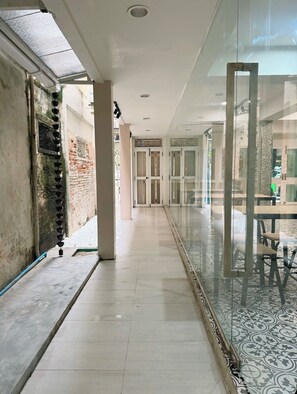 A corridor with a glass partition, tiled flooring, and a patterned floor design. - Via Si Phraya (Bangkok)