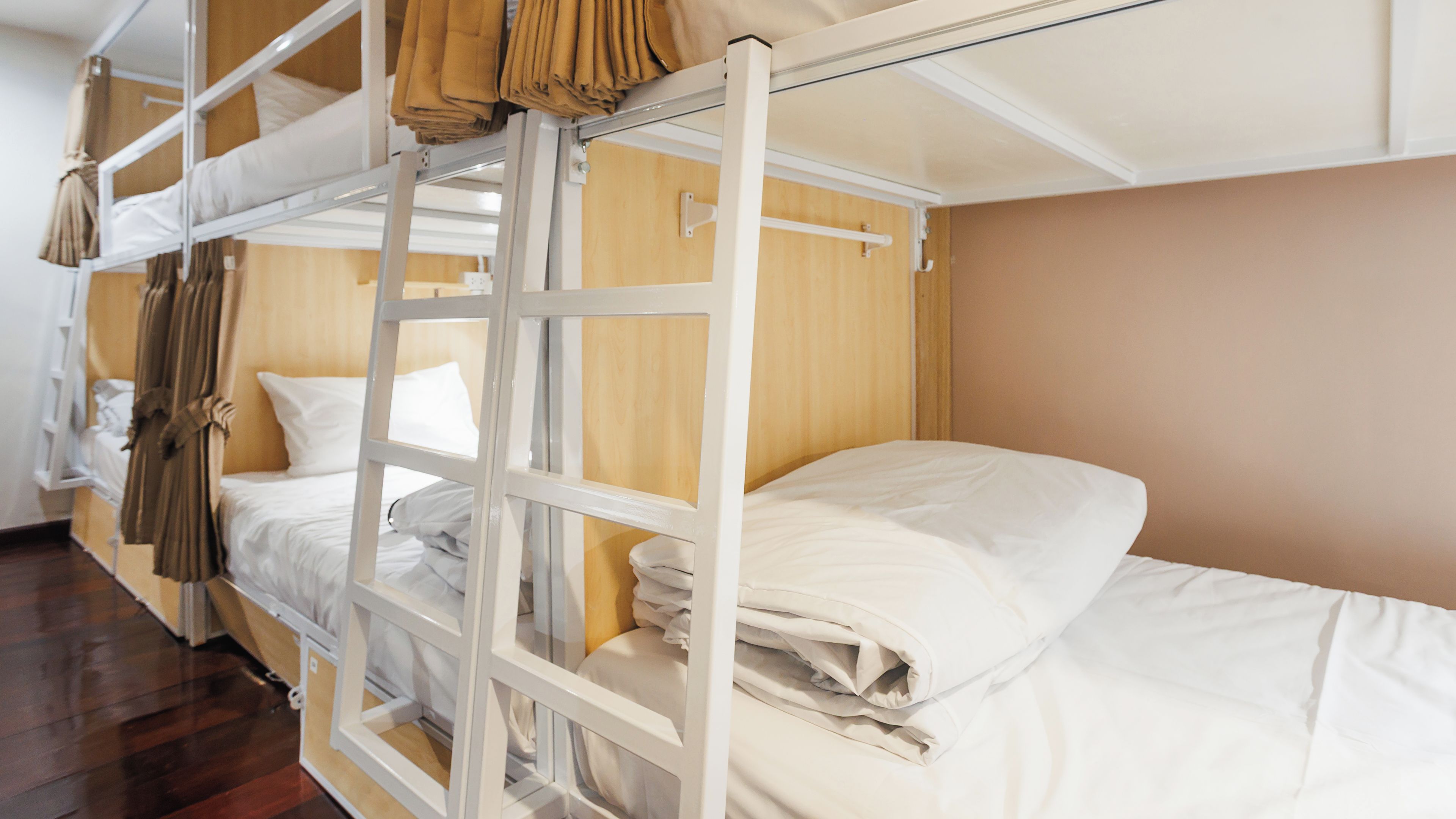 A bunk bed room with a ladder, a wooden wall, and a white bed.
