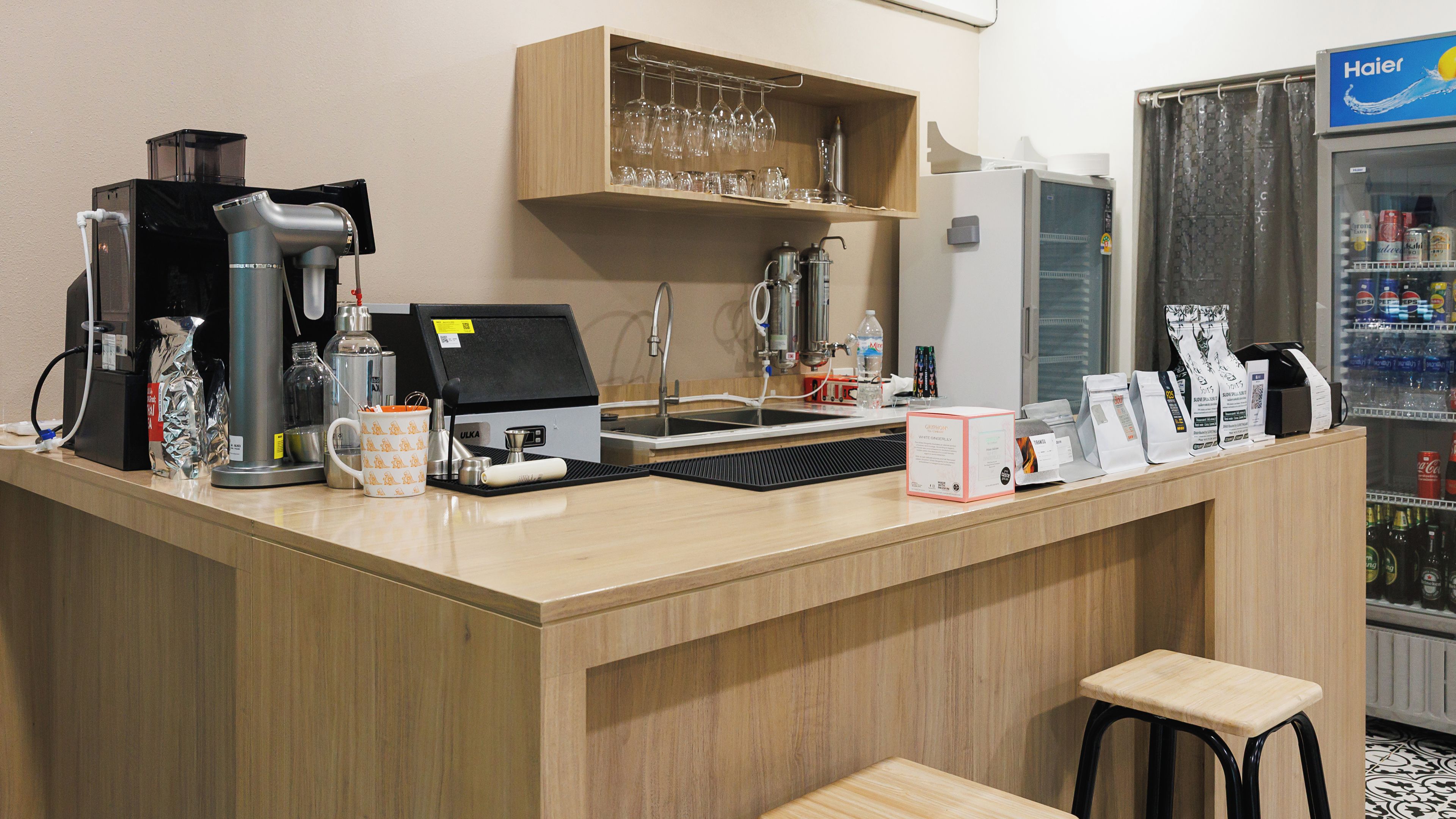 A bar area with a coffee machine, a glass display, and a beverage dispenser.