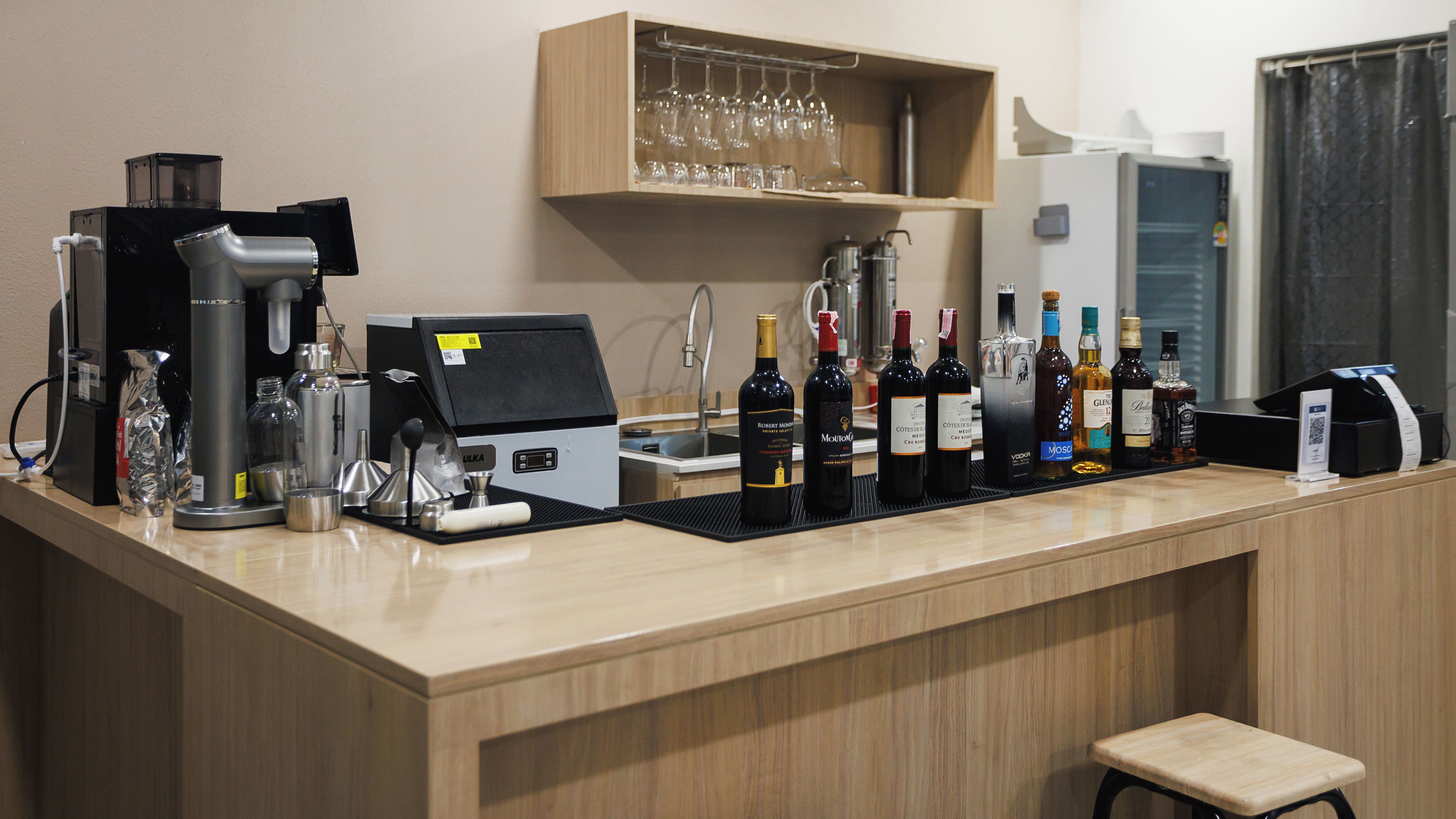 A bar area with a coffee machine, wine bottles, and a cash register.