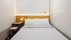 A hotel room with a bed, a nightstand with a lamp, and a wooden headboard. - Via Si Phraya (Bangkok)