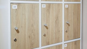 A row of wooden lockers with numbered labels, each with a round knob and a keyhole. - Via Si Phraya (Bangkok)