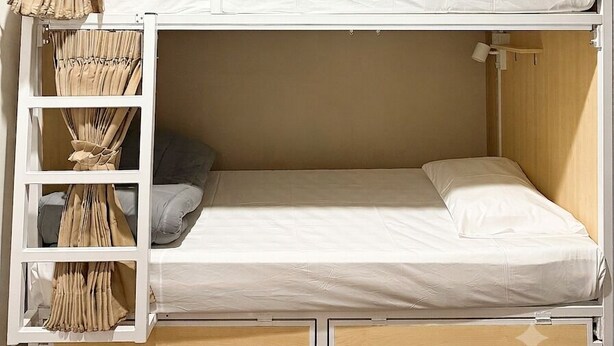 Una litera con ventilador de techo, una escalera y cajones para guardar objetos.