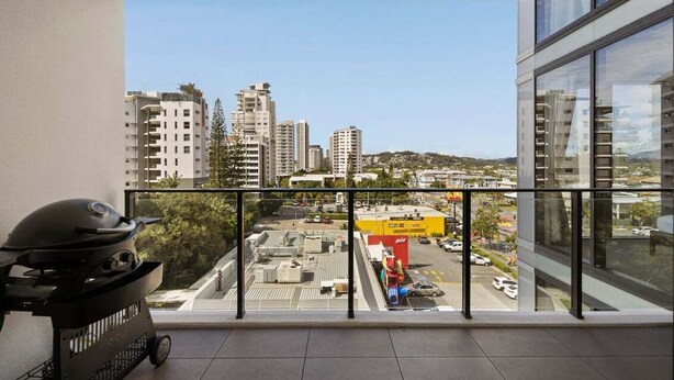 A balcony with a view of a cityscape, a barbecue grill, and a large window. - Sea Glimpse Escape at Sandbar Burleigh (Gold Coast)