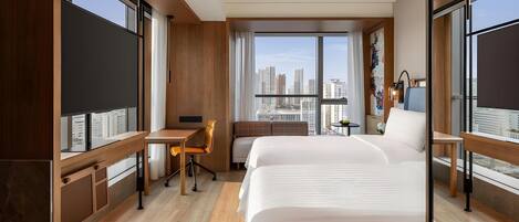 A hotel room with a large bed, a desk, and a view of the cityscape.