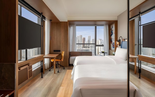 Habitación de hotel con una cama grande, un escritorio y vistas a la ciudad.