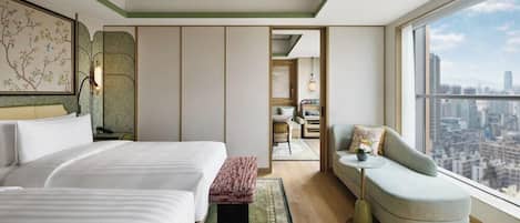 Habitación de hotel moderna con dos camas, un sofá, vistas a la ciudad y una obra de arte tradicional en la pared.