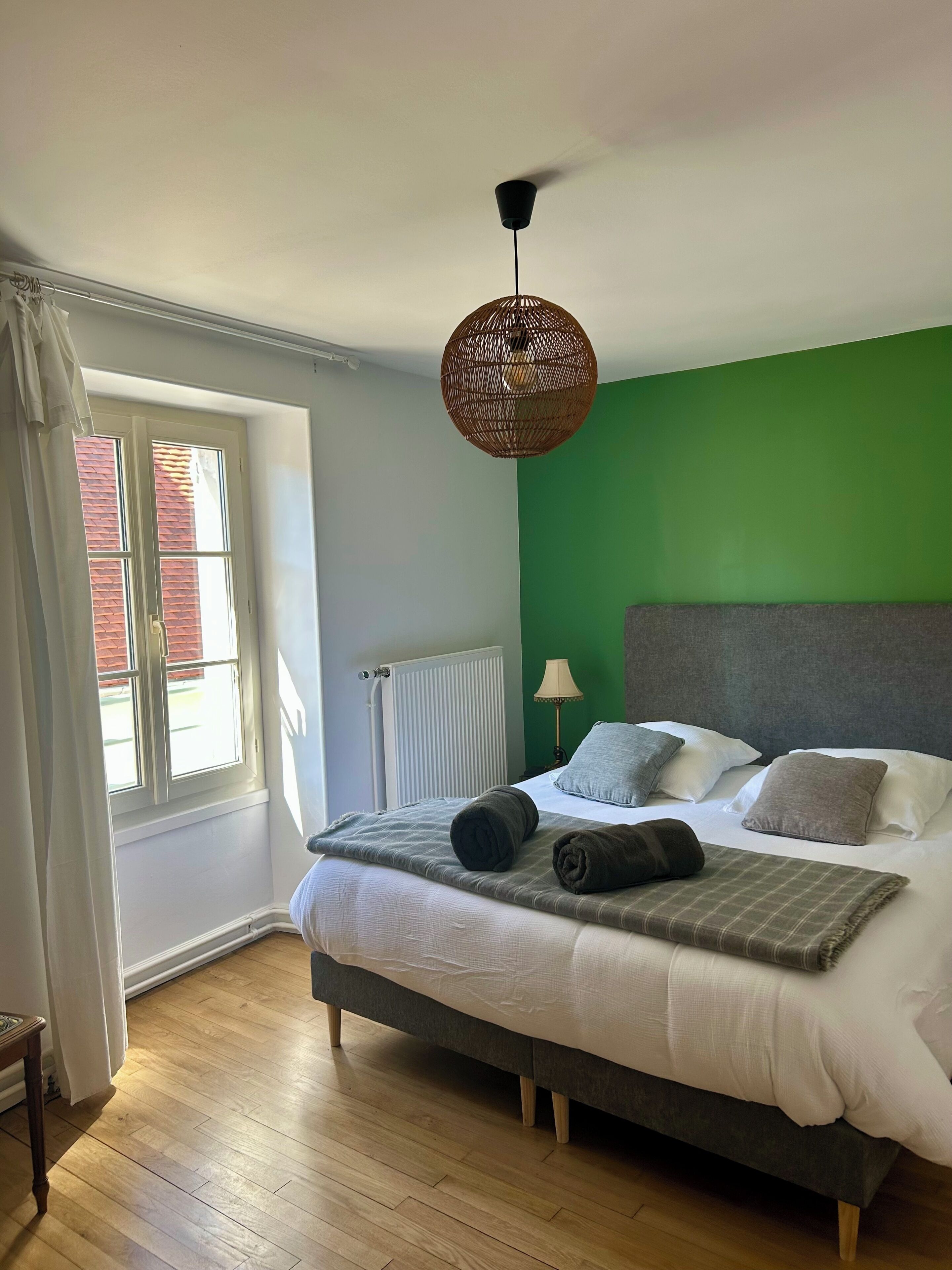 A bedroom with a bed, a window, a radiator, and a ceiling fan.