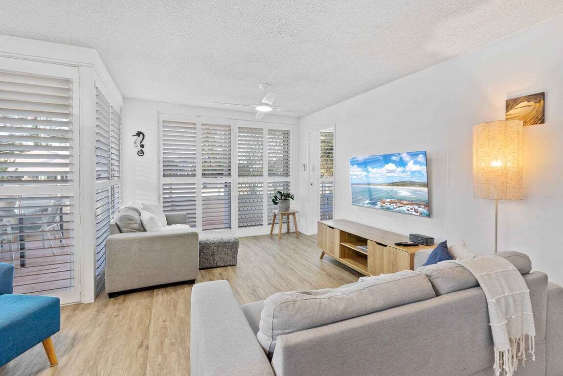 A modern living room with a sofa, TV, and a lamp.