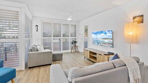 Ein modernes Wohnzimmer mit Sofa, Fernseher und Lampe.