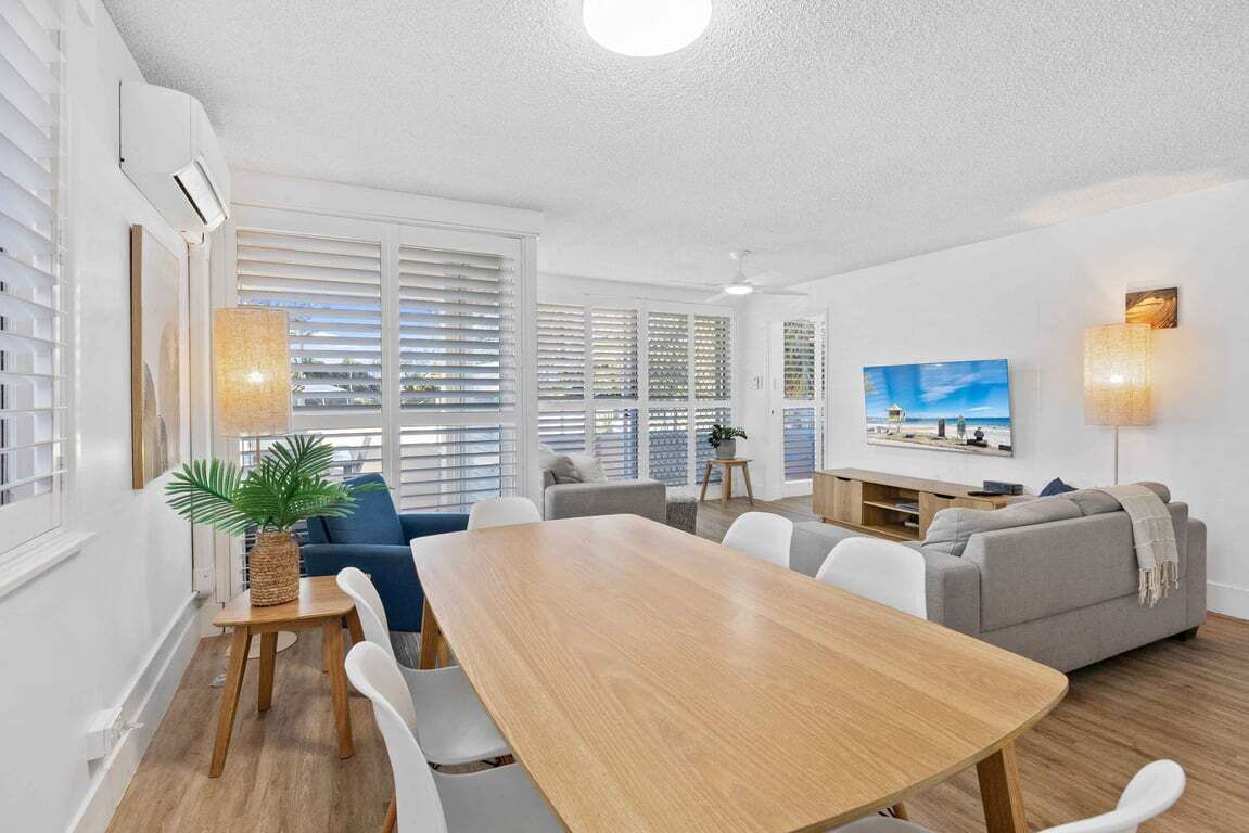 Ein modernes Wohnzimmer mit Esstisch, Sofas und einem Fernseher.