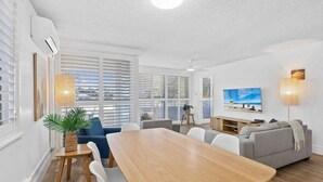 Ein modernes Wohnzimmer mit Esstisch, Sofas und einem Fernseher.