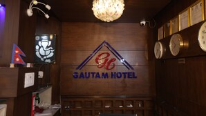 Un vestíbulo de hotel con una araña, relojes y el logotipo del Hotel Gautam.