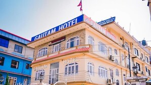 Un hotel con un llamativo letrero 'CAUTAM HOTEL', varias ventanas y una entrada con portón.