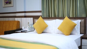 A hotel room with a bed, two pillows, a bedside table, a chair, and a window with curtains. - Gautam Hotel  Bardibas (Bardibas)