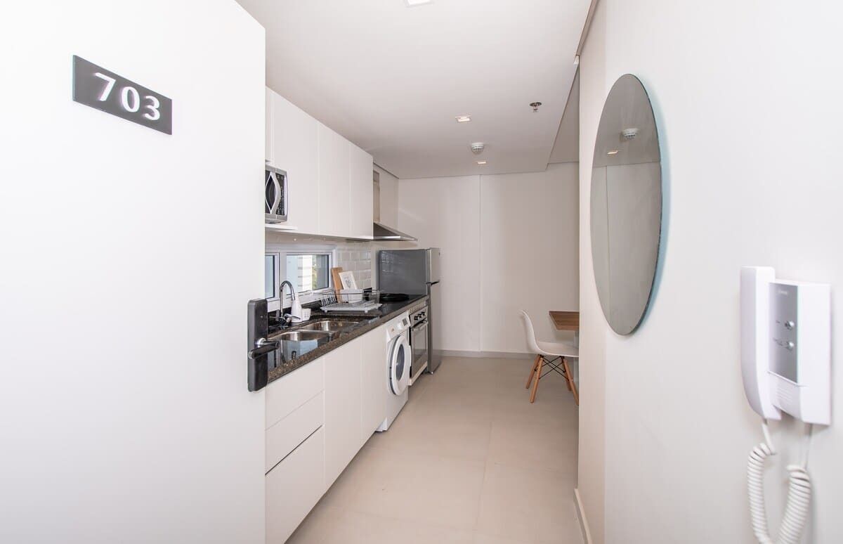 Cocina compacta con lavadora, microondas y teléfono en la pared.