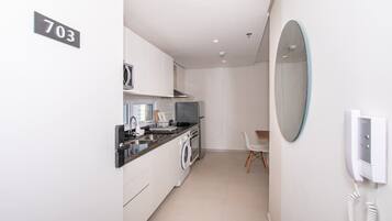 Cocina compacta con lavadora, microondas y teléfono en la pared.