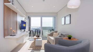 Una sala de estar moderna con un sofá, una mesa de centro, televisor y un balcón con vista a la ciudad.