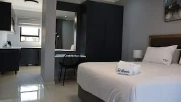 A hotel room with a bed, a desk, a chair, a mirror, and a painting on the wall.