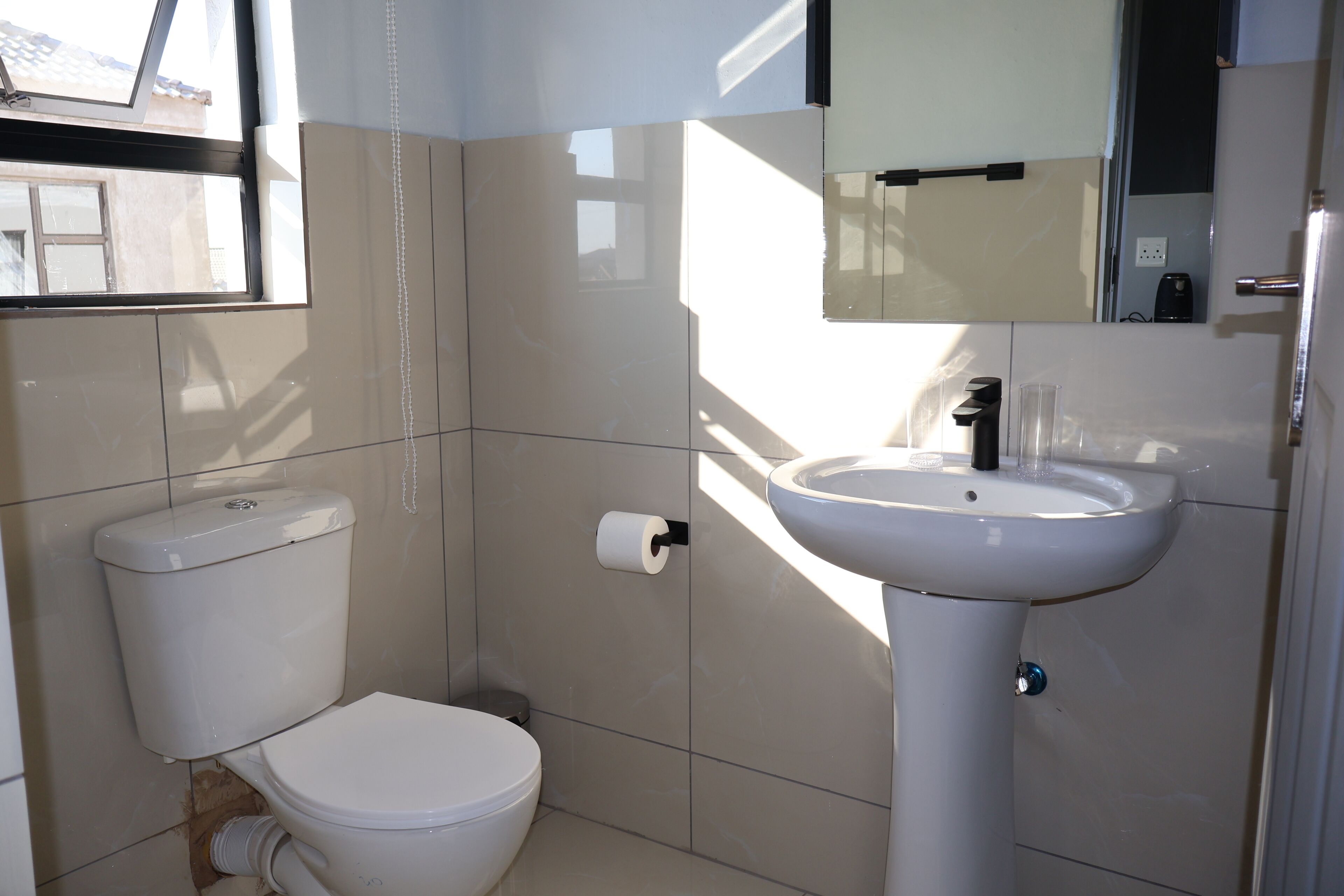 Un baño con inodoro, lavamanos y espejo.