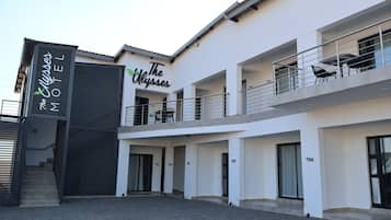 A modern hotel with a sign reading 'The Ulysses Motel.' It features a ground floor with a covered entrance and a second floor with balconies.