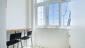 A room with a window, two black chairs, a wooden table, and patterned floor tiles. - GuestReady-Charming 3-Bedroom Lisbon Retreat (Lisbon)